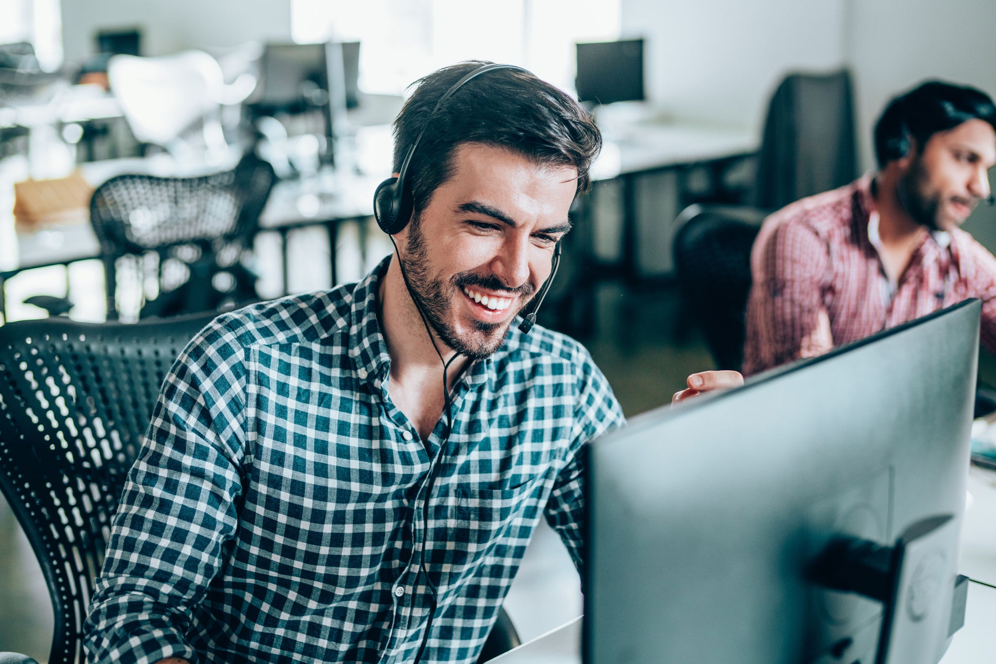 Cheerful young man working in a call center with his team