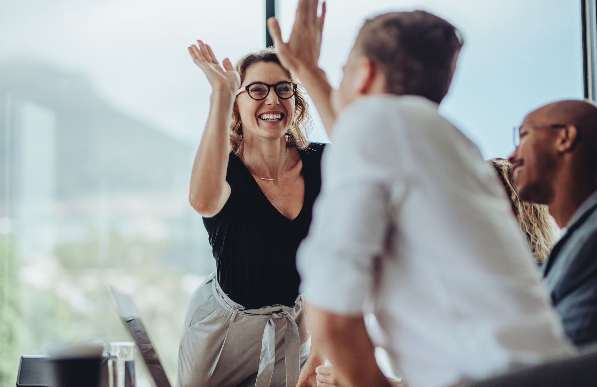 Businesswoman giving a high five to male colleague in meeting. Business professionals high five during a meeting in boardroom.