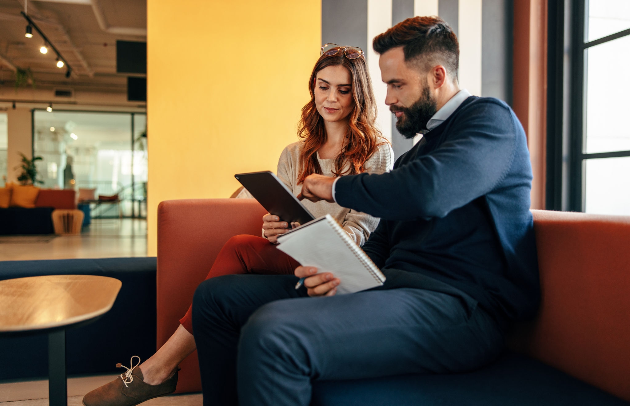 Two focused businesspeople using a digital tablet in an office lobby. Two modern businesspeople having an important discussion in a co-working space. Young entrepreneurs collaborating on a new project.