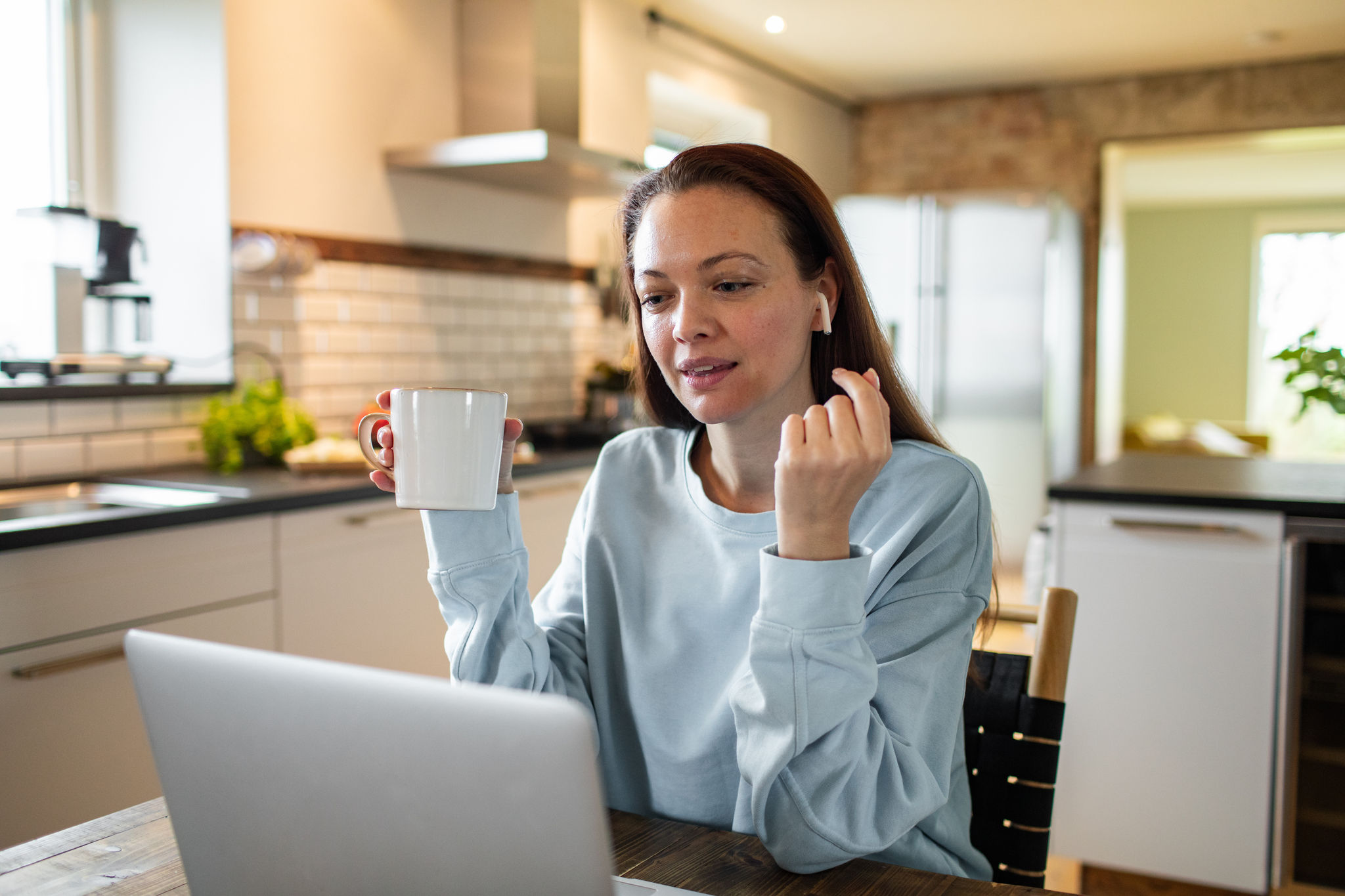 Close up of a young adult woman having a video call on a laptop in a kitchen