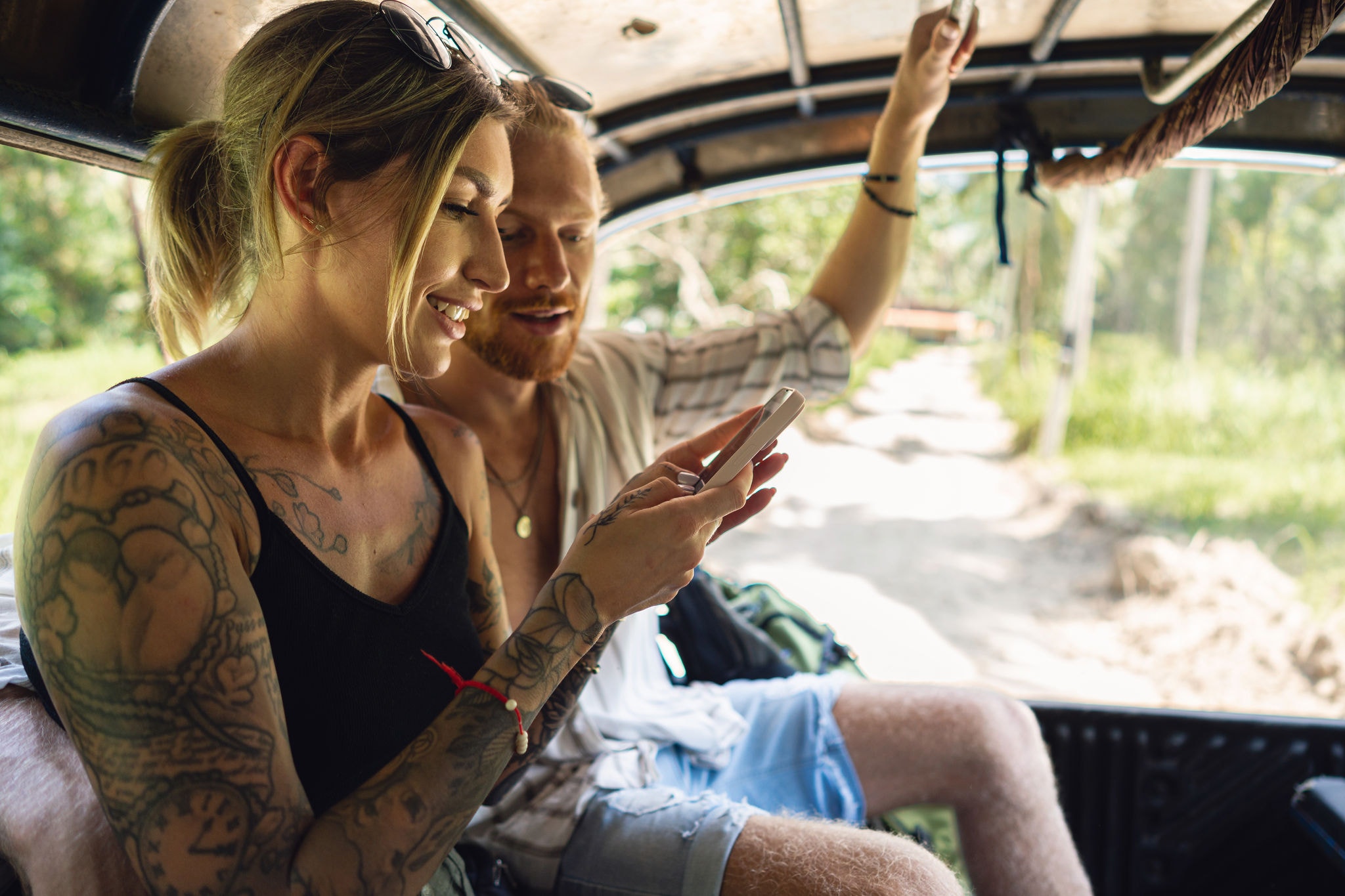 Young Caucasian couple travel together, in the off road taxi, during their vacation while using mobile phone