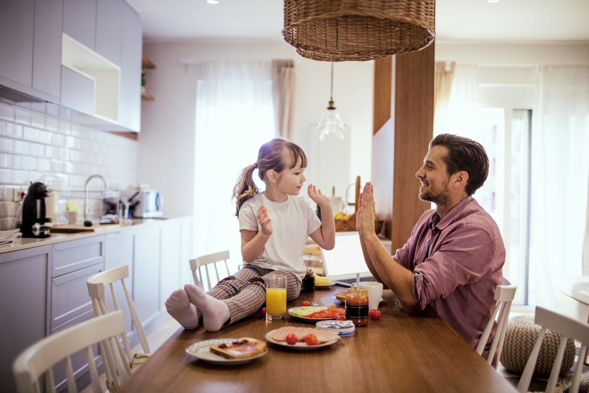 Father and daughter sitting in the dining room, eating and playing together