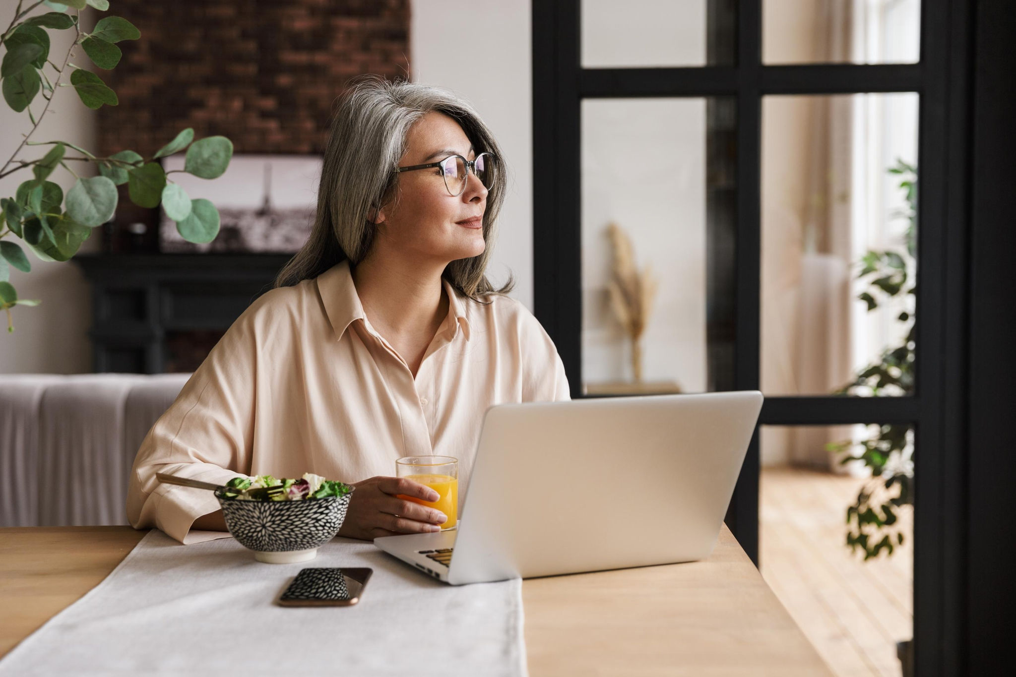 Woman working at home looking outside her window 