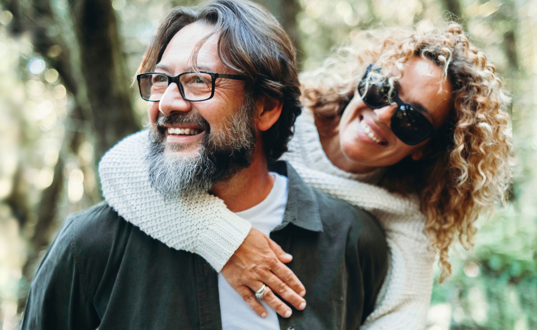Youthful mature people enjoying weekend activity together. Man carrying woman in piggyback and having fun with love. Man wearing glasses and woman hugging him. Happy life and relationship. Together