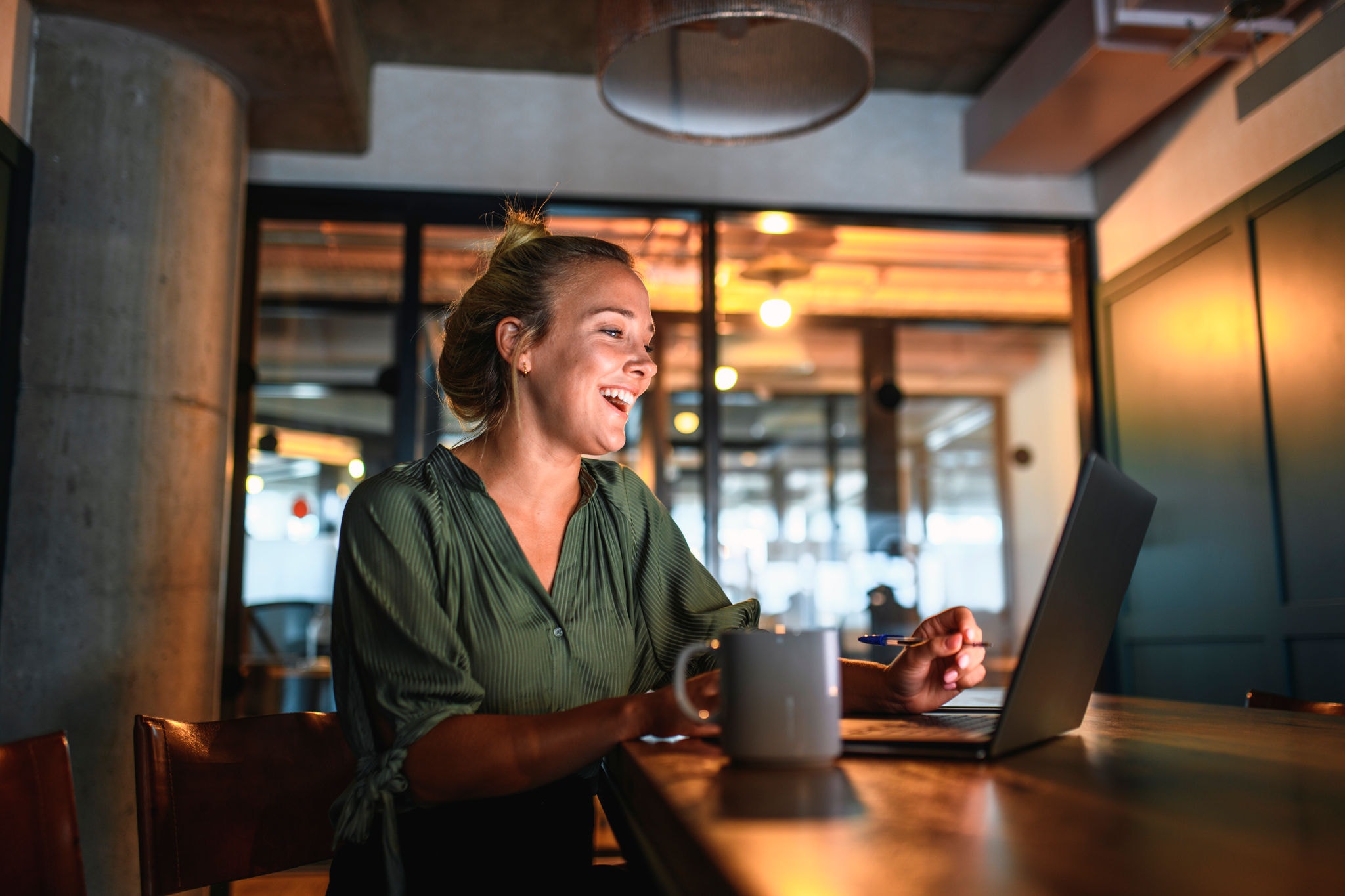 Young woman smiling on virtual call on laptop in dimly lit room
