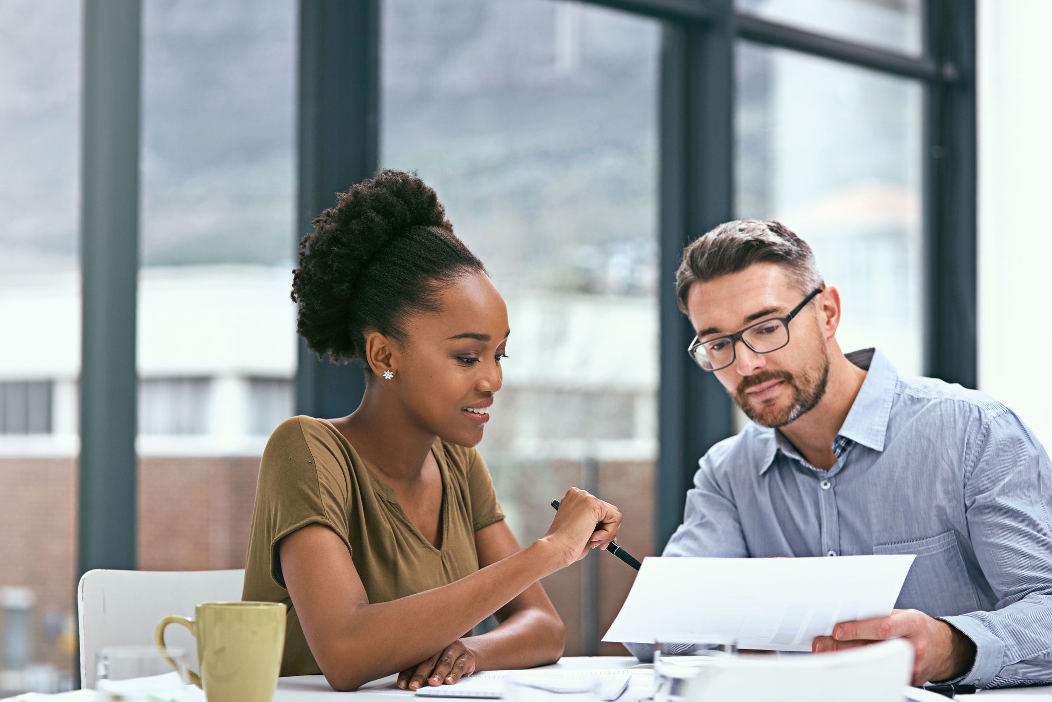 Two colleagues in a meeting room looking at a report together