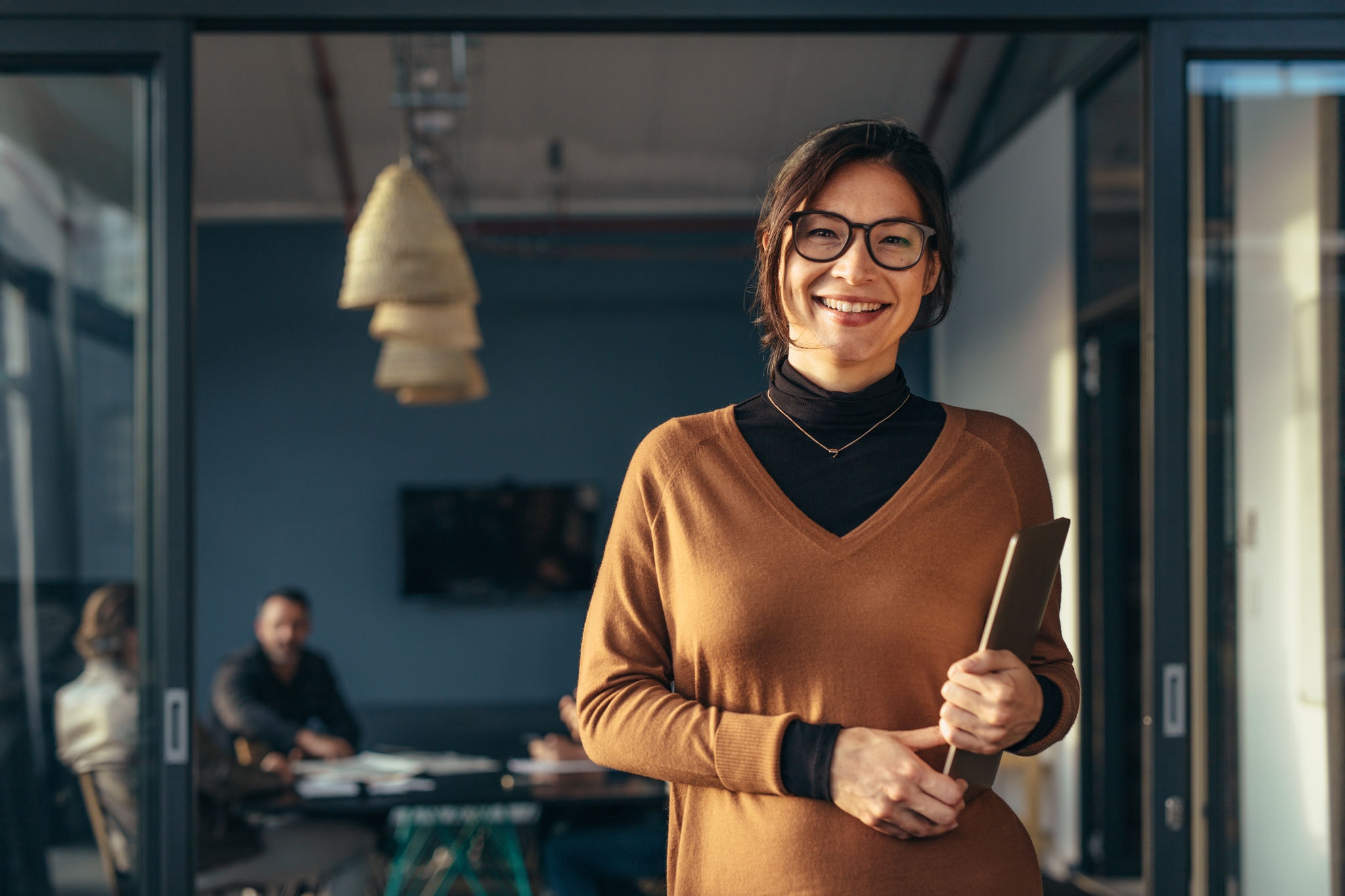 Smiling female worker holding a laptop standing in the office 