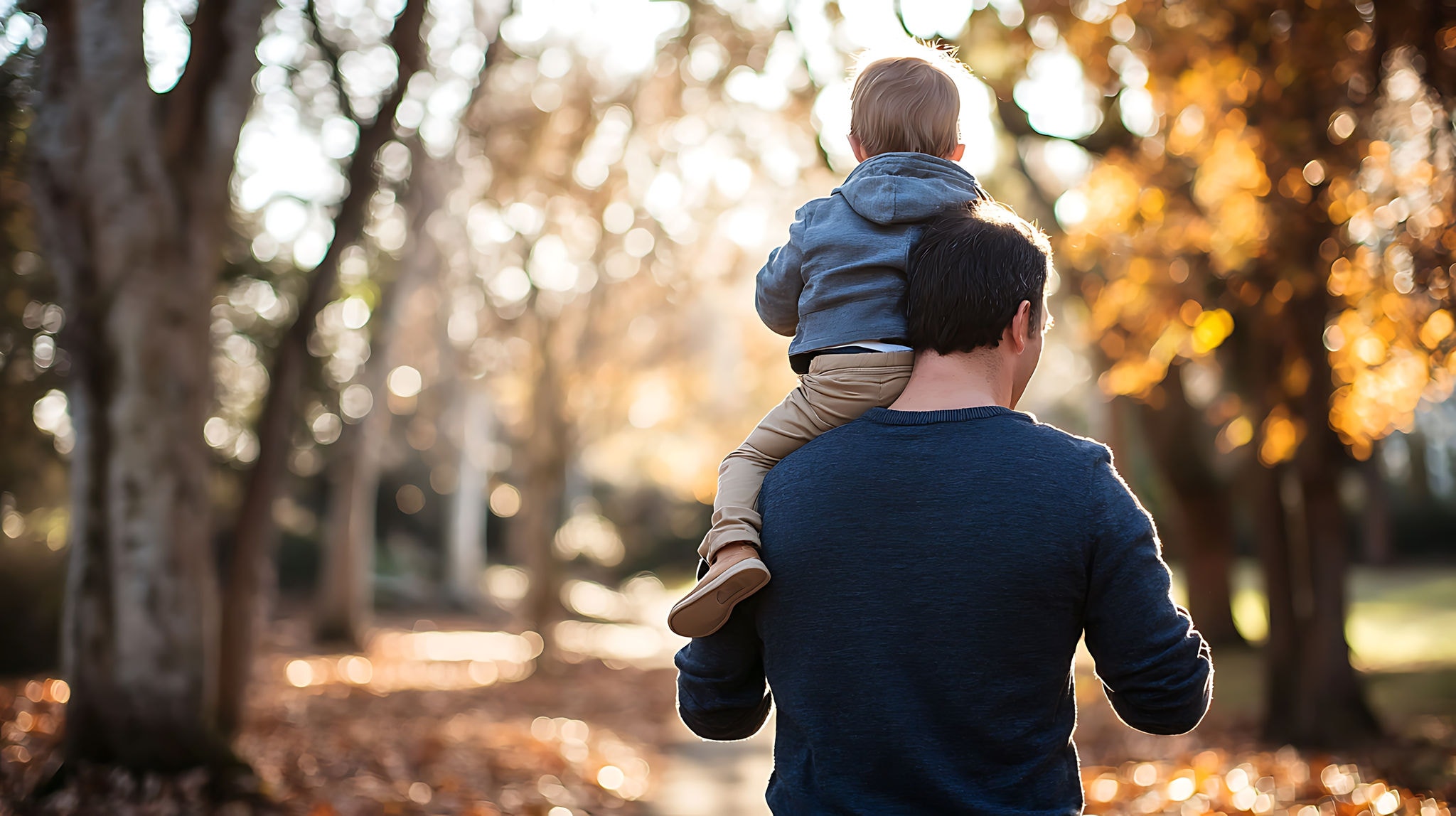 Father walking in a park with child on his shoulder