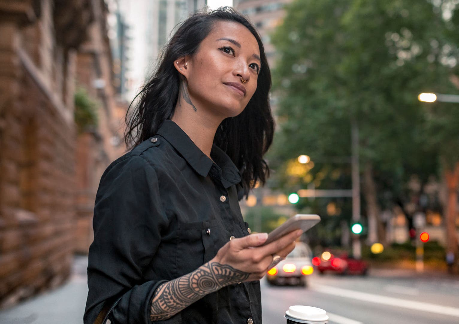 Young woman with a coffee on the street waiting for taxi