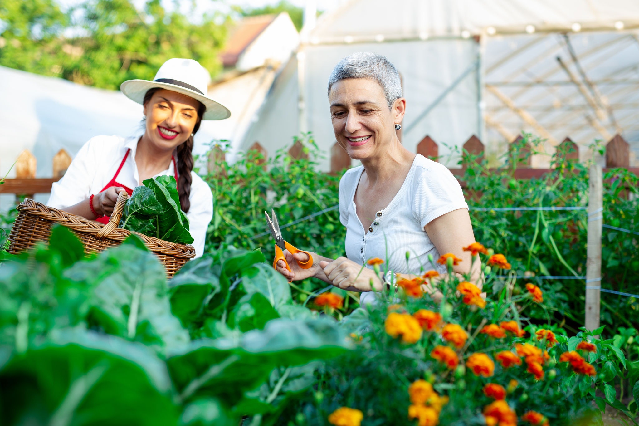 Mother and daughter with freshly harvested vegetables in their garden.
