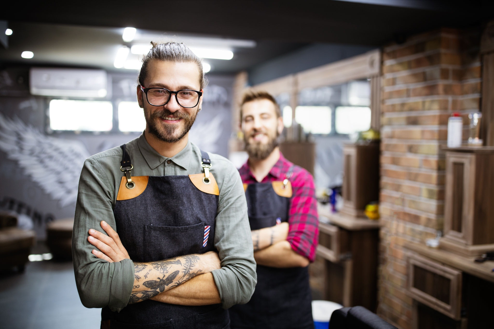 Portrait of tattooed young male barbers and hairdressers in barber shop