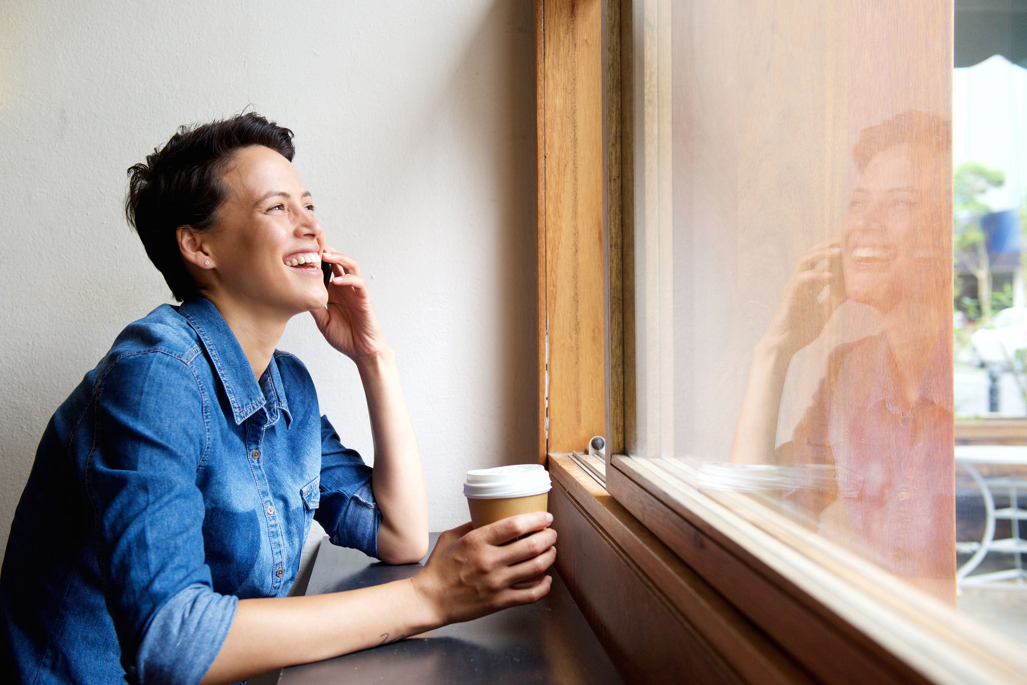 Young woman talking on mobile phone with a takeaway coffee