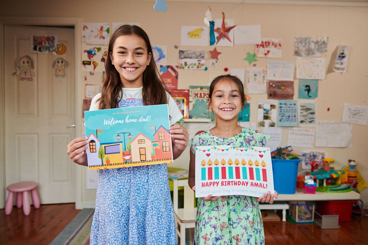 Two girls at childcare smiling and showing their pictures